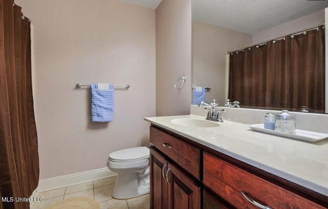 bathroom with toilet, a textured ceiling, vanity, tile patterned flooring, and baseboards