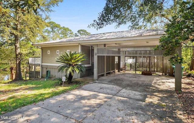 view of front of property featuring a carport, fence, metal roof, and concrete driveway