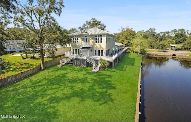 back of house with a yard, a water view, fence, a balcony, and stairs