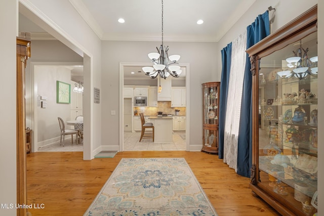 interior space featuring an inviting chandelier, light hardwood / wood-style flooring, and ornamental molding