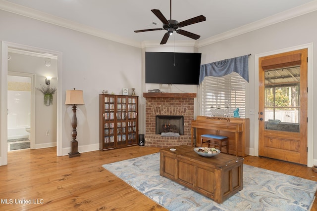 living room featuring ceiling fan, light hardwood / wood-style floors, ornamental molding, and a fireplace