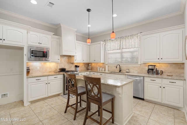 kitchen with a center island, decorative light fixtures, light stone counters, white cabinetry, and stainless steel appliances