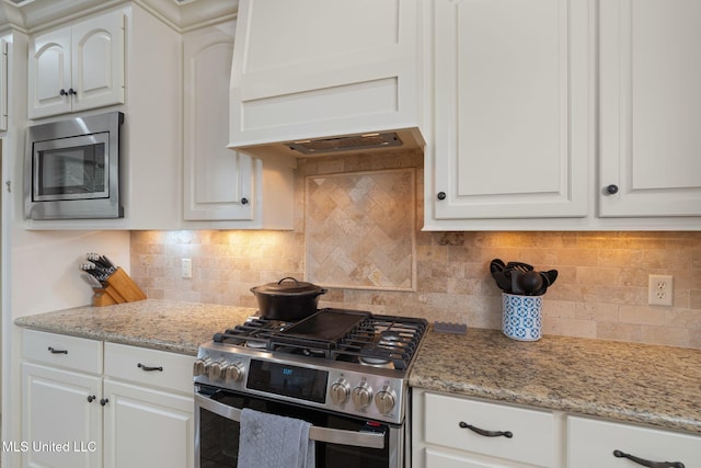 kitchen featuring decorative backsplash, appliances with stainless steel finishes, white cabinetry, and light stone counters