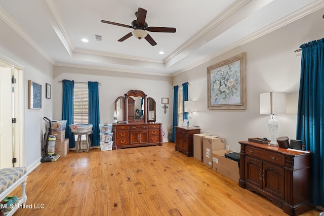 interior space featuring a raised ceiling, ceiling fan, light wood-type flooring, and ornamental molding