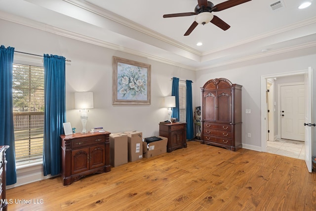 bedroom featuring a tray ceiling, ceiling fan, light hardwood / wood-style floors, and ornamental molding