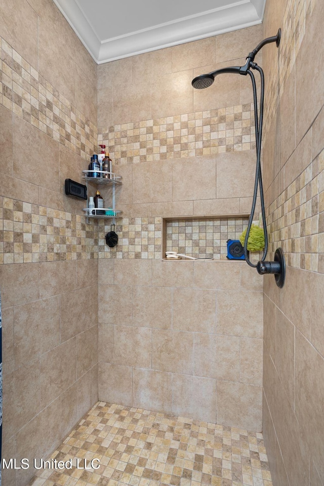 bathroom with a tile shower and crown molding