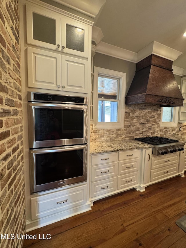 402 Ironwood Pl, Madison, MS 39110 - kitchen with light stone counters, white cabinetry, premium range hood, crown molding, and stainless steel appliances
