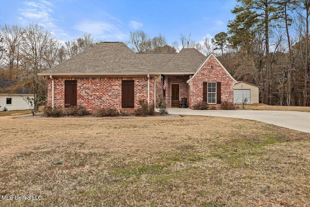 view of front of property featuring a garage, a front yard, and an outbuilding