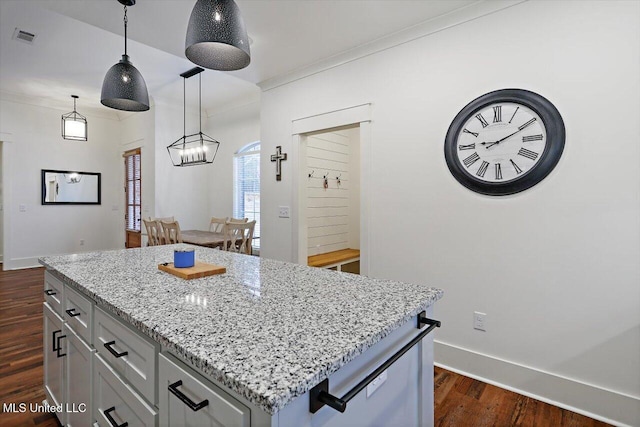 kitchen with decorative light fixtures, dark hardwood / wood-style floors, light stone countertops, and a kitchen island