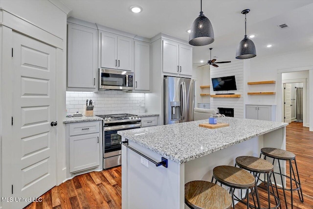 kitchen featuring light stone counters, white cabinetry, stainless steel appliances, and a kitchen island