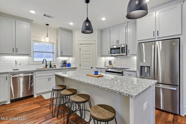 kitchen with white cabinets, a kitchen island, stainless steel appliances, tasteful backsplash, and sink