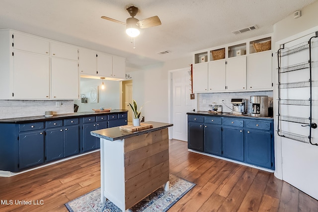 kitchen featuring blue cabinetry, dark countertops, visible vents, and white cabinets