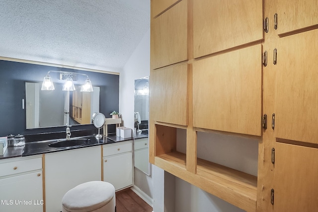 bathroom featuring a textured ceiling, lofted ceiling, and vanity