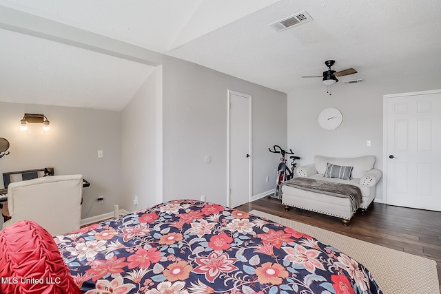 bedroom with a textured ceiling, visible vents, vaulted ceiling, and dark wood-style flooring