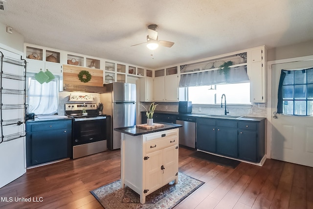 kitchen with stainless steel appliances, dark countertops, white cabinets, and a sink