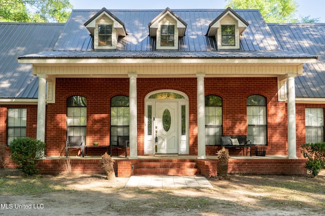 view of front of property with a porch, brick siding, and metal roof