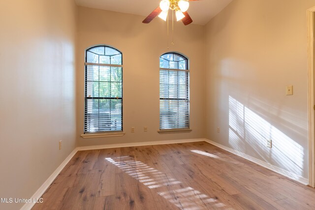 empty room with wood finished floors, ceiling fan, and baseboards