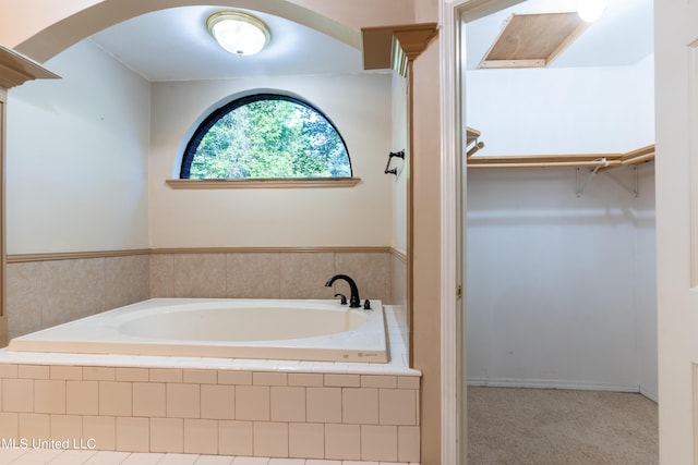 full bathroom with a walk in closet and a bath