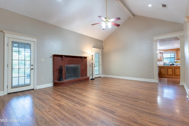 unfurnished living room with ceiling fan, a fireplace, wood finished floors, beamed ceiling, and high vaulted ceiling
