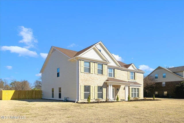 view of front facade featuring a front lawn, fence, and brick siding