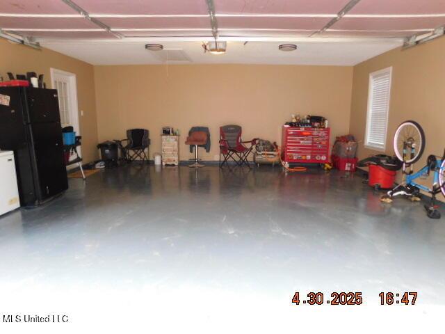 5881 Morganton Dr, Olive Branch, MS 38654 - garage featuring freestanding refrigerator and a garage door opener