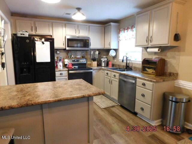 5881 Morganton Dr, Olive Branch, MS 38654 - kitchen with light wood-type flooring, light countertops, a sink, backsplash, and stainless steel appliances
