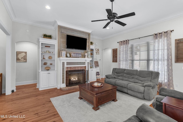 living room featuring ornamental molding, a brick fireplace, ceiling fan, and light hardwood / wood-style floors