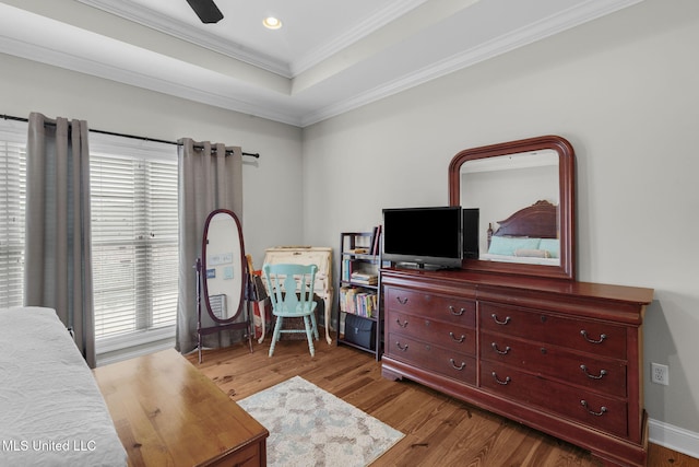 bedroom with multiple windows, hardwood / wood-style flooring, a tray ceiling, and crown molding