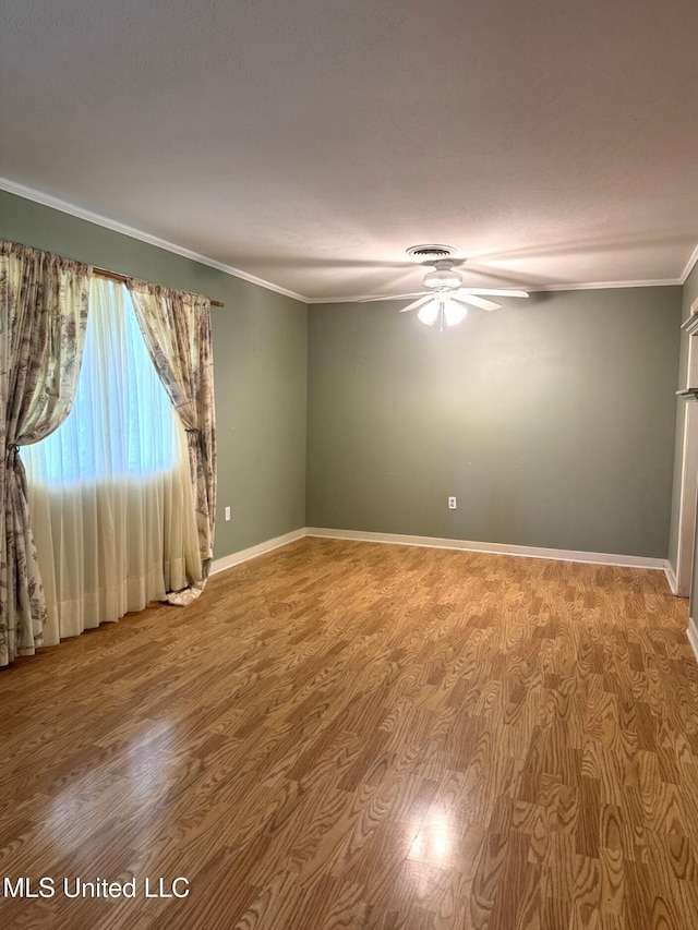 spare room featuring a ceiling fan, ornamental molding, baseboards, and wood finished floors