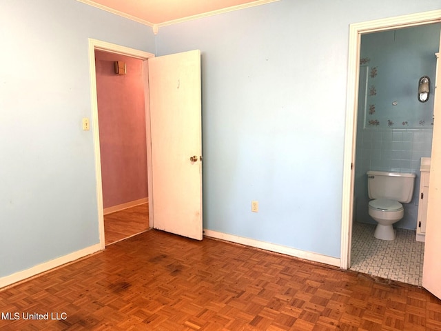 unfurnished bedroom with baseboards, ornamental molding, and connected bathroom