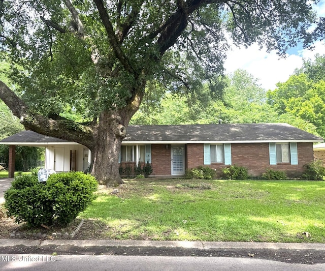 ranch-style house featuring a front yard, brick siding, and a carport