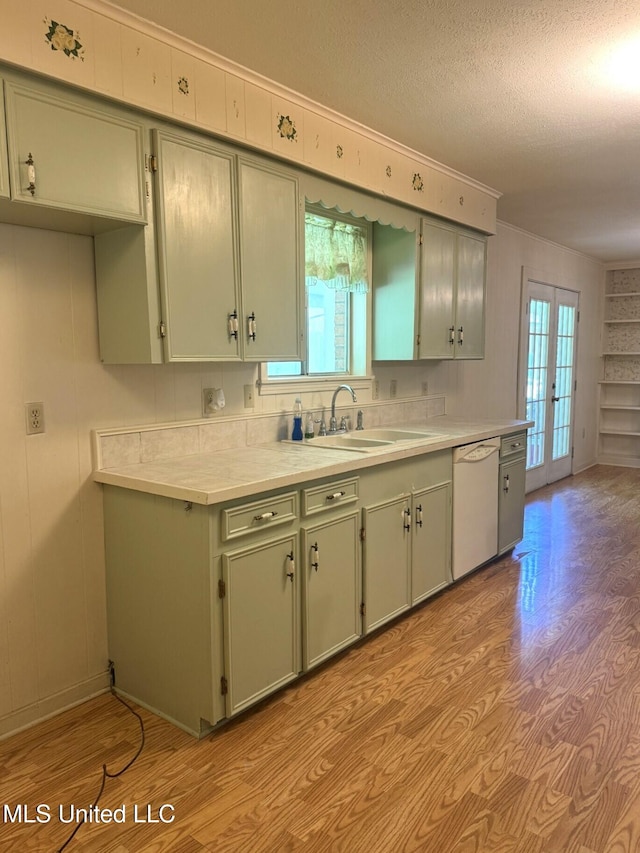 kitchen featuring a sink, light wood finished floors, light countertops, and white dishwasher