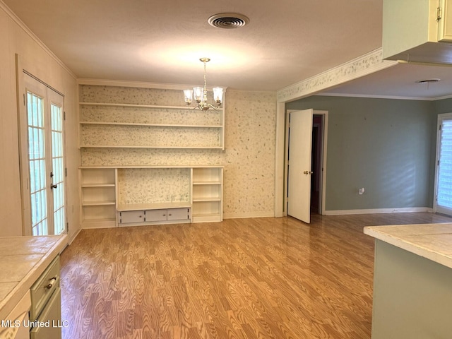 unfurnished dining area with light wood finished floors, crown molding, and visible vents