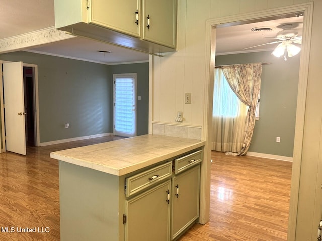 kitchen with ornamental molding, tile countertops, and light wood-style flooring