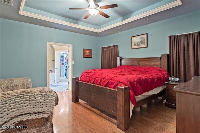 bedroom with ceiling fan, a raised ceiling, ensuite bath, and light hardwood / wood-style flooring