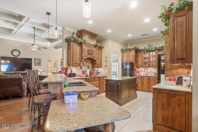 kitchen with pendant lighting, coffered ceiling, a kitchen island, a kitchen bar, and kitchen peninsula