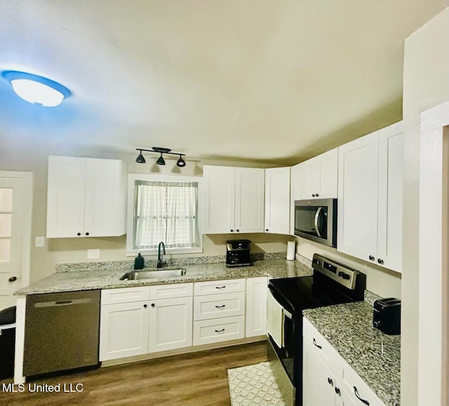 kitchen with sink, appliances with stainless steel finishes, white cabinets, and dark hardwood / wood-style flooring