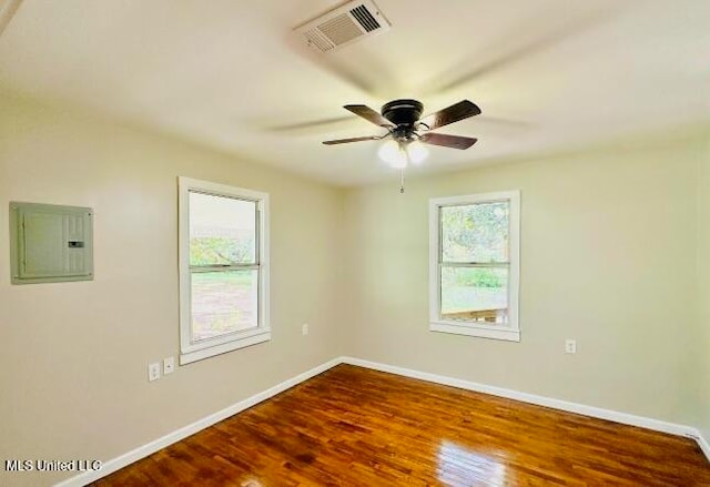 empty room with electric panel, wood-type flooring, and ceiling fan