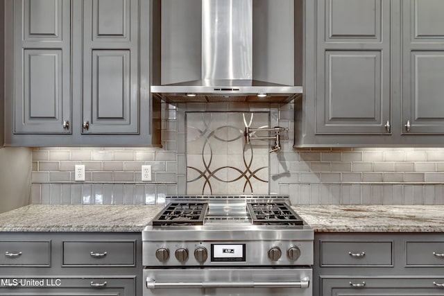 101 Commons Pl, Ridgeland, MS 39157 - kitchen featuring wall chimney range hood, tasteful backsplash, stainless steel stove, and gray cabinets