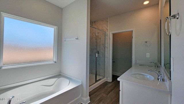 bathroom with a stall shower, wood finished floors, a sink, and a bath