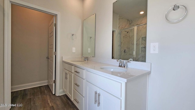 full bath with double vanity, wood finished floors, a sink, and a shower stall