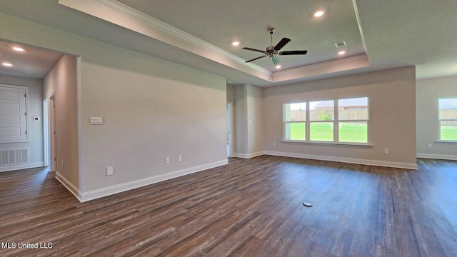 interior space featuring dark wood-style floors, a tray ceiling, visible vents, and crown molding