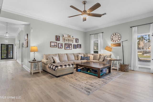 living room with a healthy amount of sunlight, light hardwood / wood-style floors, and crown molding