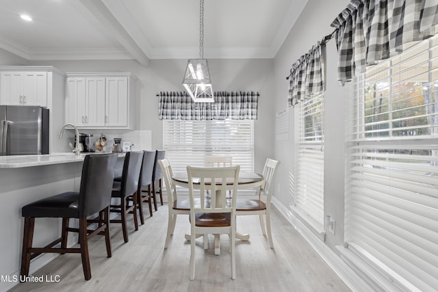 dining space featuring crown molding, beamed ceiling, and light wood-type flooring