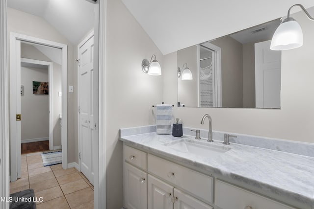 bathroom with tile patterned flooring, vanity, and lofted ceiling