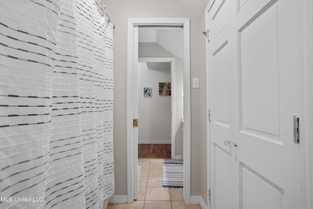 hallway featuring light tile patterned floors and lofted ceiling