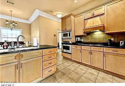 kitchen featuring premium range hood, stainless steel appliances, dark countertops, and visible vents