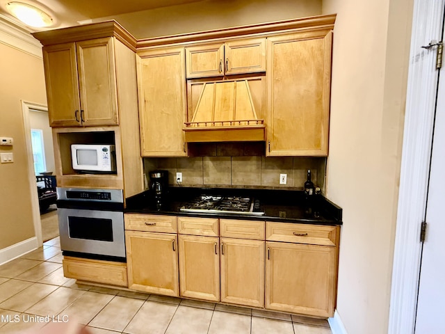 kitchen featuring dark countertops, baseboards, light tile patterned floors, decorative backsplash, and stainless steel appliances