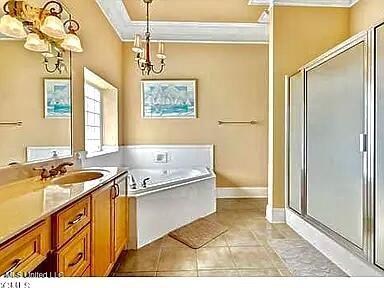 full bathroom with a shower stall, tile patterned flooring, crown molding, a bath, and vanity