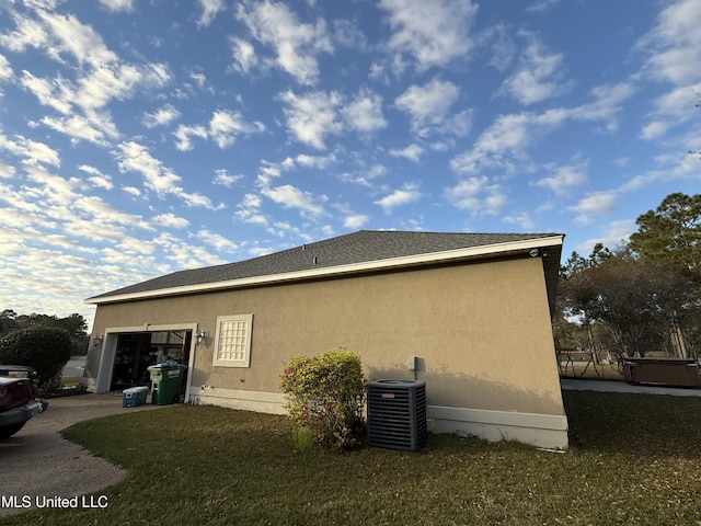 view of side of property featuring central air condition unit, stucco siding, an attached garage, and concrete driveway